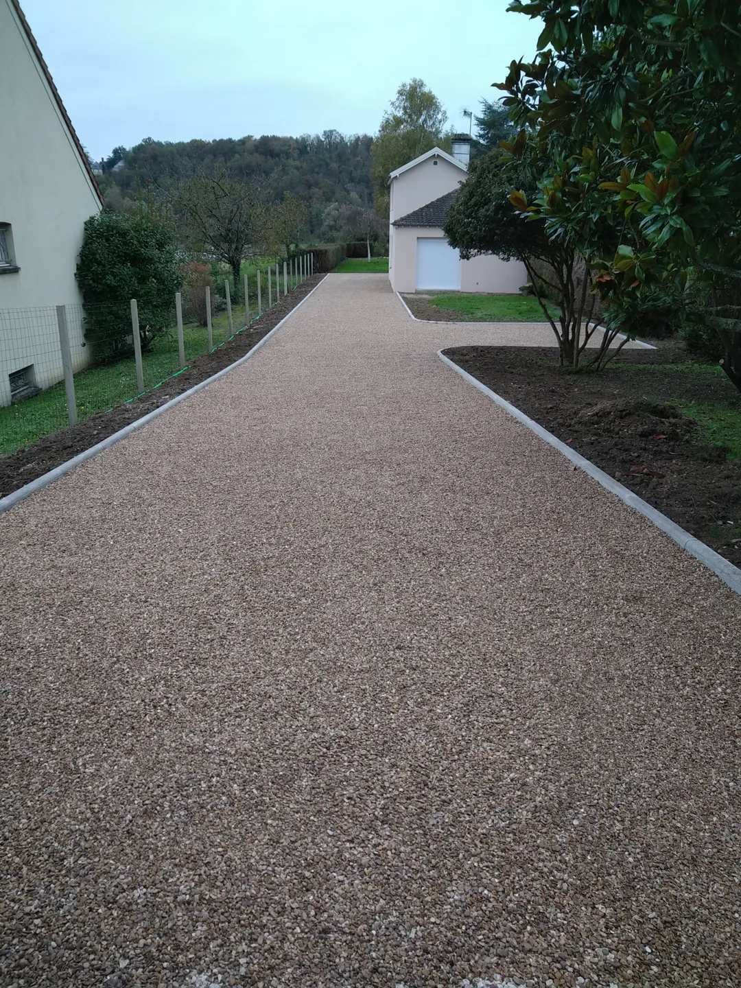 Allée gravillonnée neuve bordée de plantations